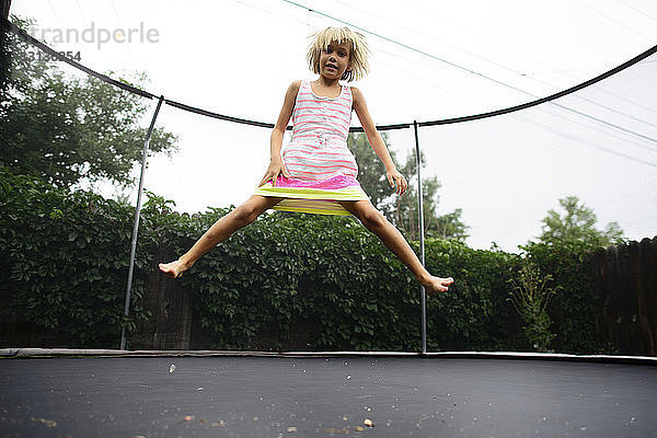 Niedrigwinkel-Porträt eines Mädchens  das auf einem Trampolin im Park vor klarem Himmel springt