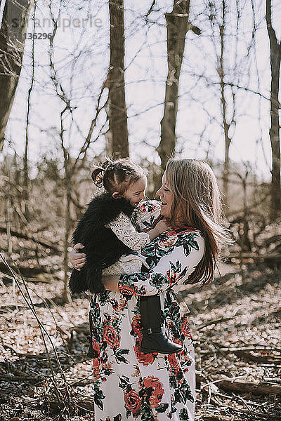 Schwangere Mutter trägt Tochter im Wald