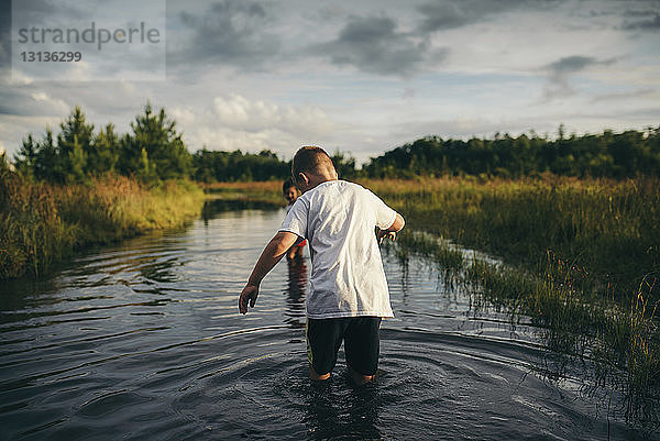 Verspielte Geschwister laufen im Kanal gegen bewölkten Himmel