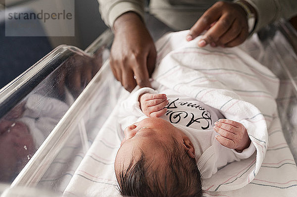 Beschnittenes Bild einer Person  die die Decke eines Neugeborenen anpasst