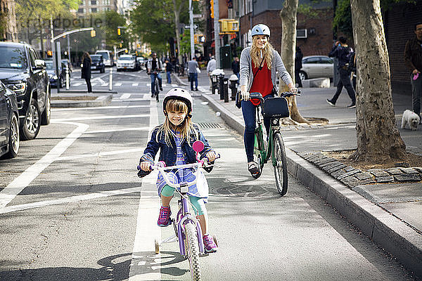 Portrait von Mutter und Tochter beim Fahrradfahren auf der Straße