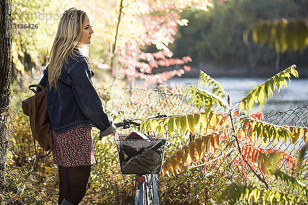Nachdenkliche Frau mit Fahrrad schaut weg  während sie im Park steht