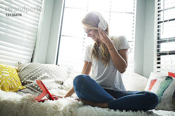 Frau hört Musik  während sie auf einem Fensterplatz in einer Nische sitzt