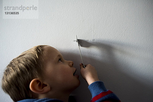 Nahaufnahme eines Jungen  der zu Hause an der Wand mit einem Spielzeug spielt