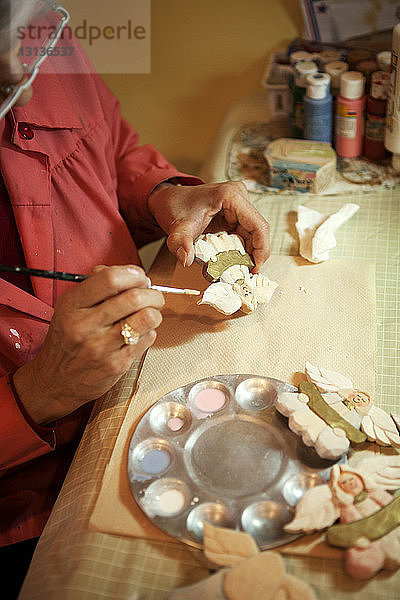 Beschnittenes Bild eines Arbeiters  der in einer Werkstatt eine Uhr herstellt