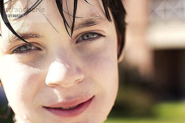 Porträt eines lächelnden nassen Jungen im Freien