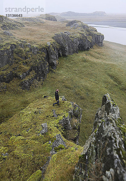 Hochwinkelaufnahme eines auf dem Berg stehenden Wanderers