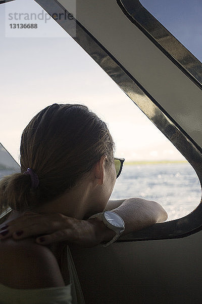 Seitenansicht einer Frau  die durch ein Bootsfenster hinaussieht