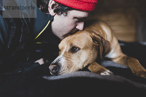 Nahaufnahme eines Mannes  der zu Hause einen Hund küsst