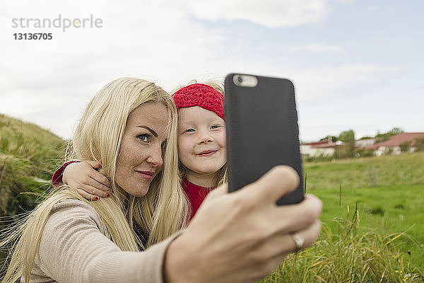 Mutter und Tochter beim Selbstfahren mit Smartphone auf dem Feld