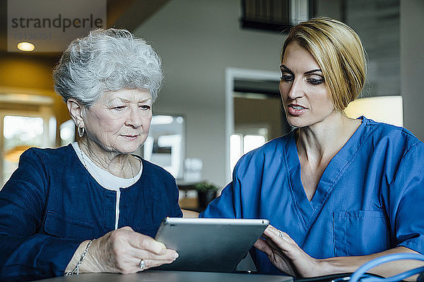 Heimpflegekraft unterstützt ältere Frau bei der Verwendung eines Tablet-Computers