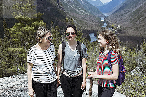 Lächelnde Mutter mit Töchtern wandert gegen Berge