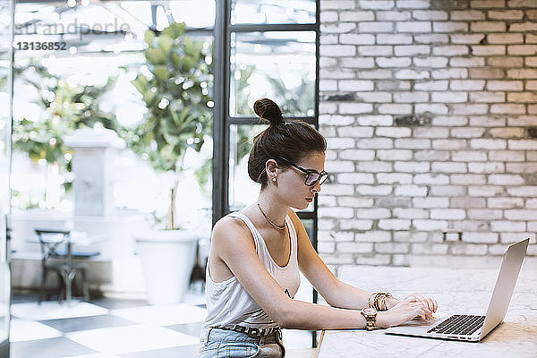 Frau arbeitet am Laptop-Computer  während sie im Café sitzt