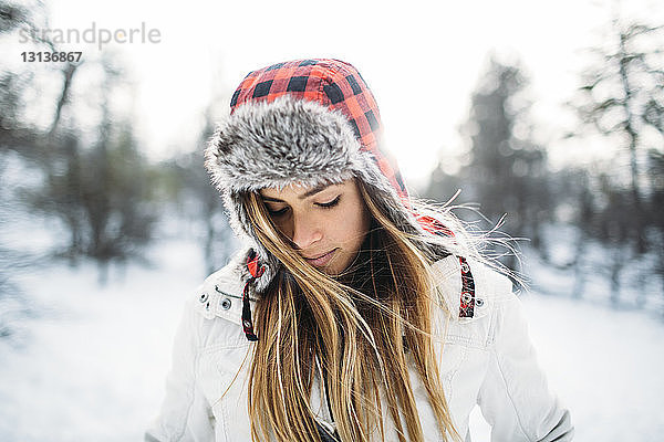 Nahaufnahme einer Frau mit Pelzmütze auf schneebedecktem Feld