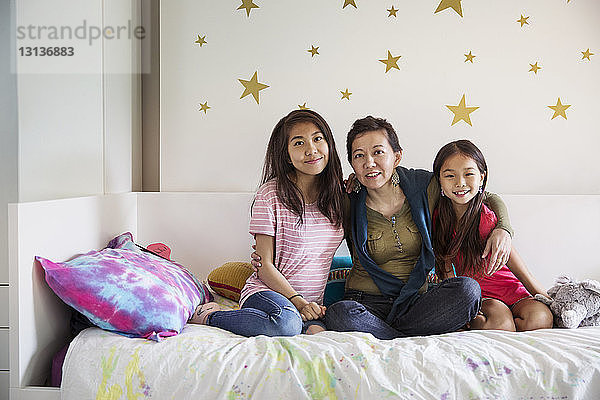 Porträt einer glücklichen Familie  die zu Hause auf dem Bett sitzt