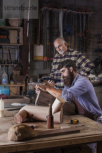 Älterer Mann betrachtet Arbeiter beim Holzschnitzen in der Werkstatt