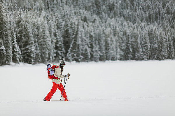 Seitenansicht einer Frau  die auf einem schneebedeckten Feld wandert