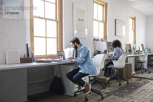 Geschäftsleute  die am Schreibtisch im Kreativbüro arbeiten