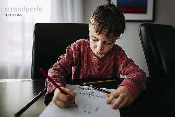 Zeichnung eines Jungen mit Buntstift auf Papier zu Hause