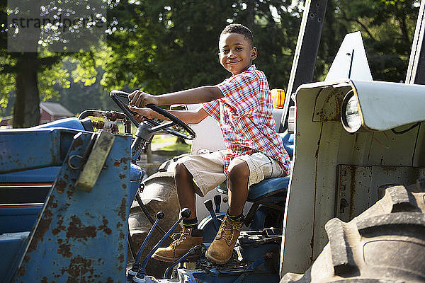 Porträt eines lächelnden Jungen  der auf einem Traktor sitzt