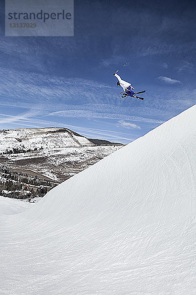 Niedrigwinkelansicht eines Skifahrers beim Skifahren auf einem schneebedeckten Berg gegen den Himmel