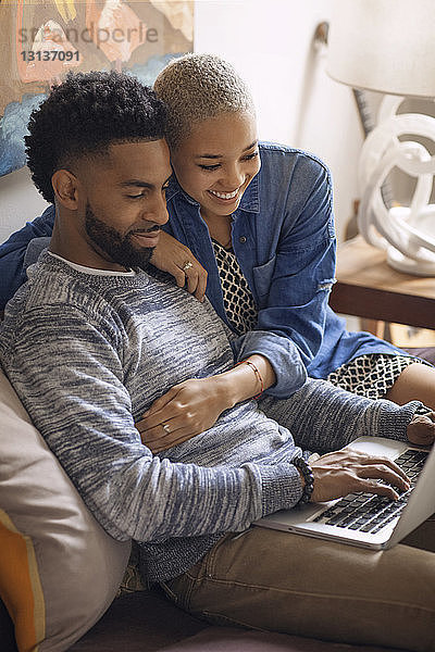 Ehepaar benutzt Laptop-Computer  während es zu Hause im Bett sitzt