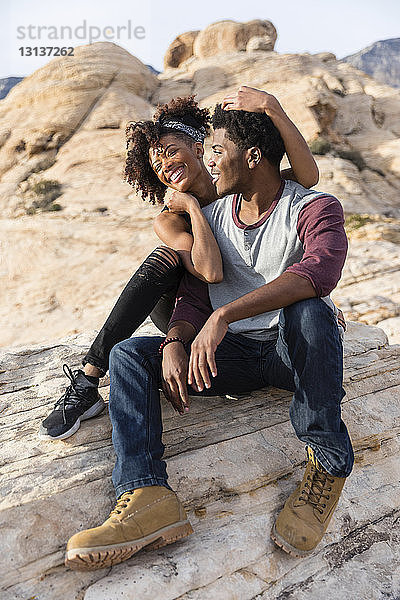 Glückliches Paar sitzt auf einer Felsformation