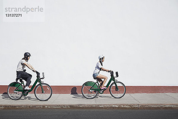 Fahrradfahren zu zweit auf dem Bürgersteig bei Sonnenschein