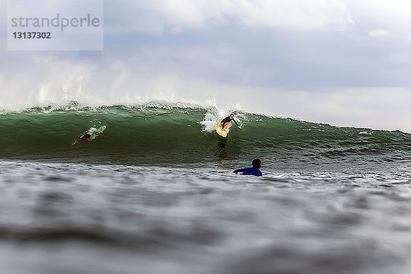 Freunde  die im Meer gegen den Himmel surfen