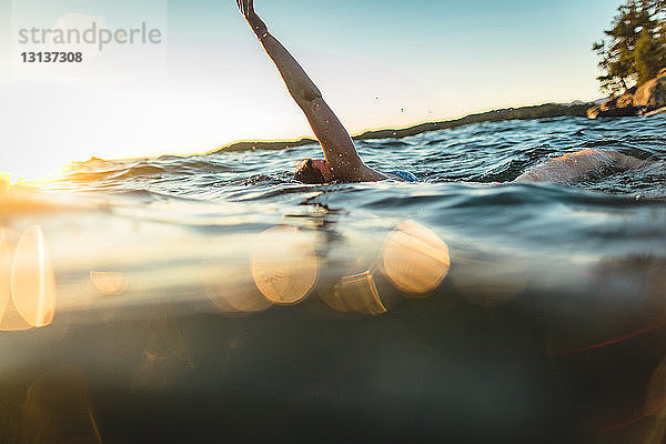 Unbeschwerte Frau schwimmt im Meer gegen den Himmel