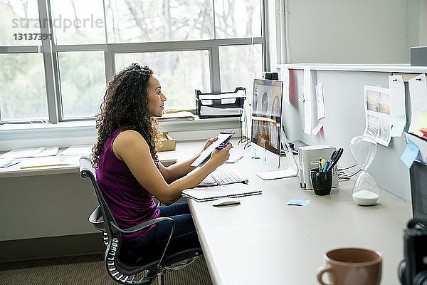 Seitenansicht einer Geschäftsfrau  die mit Kollegen diskutiert Videokonferenz mit einem Kollegen über einen Desktop-Computer im Büro