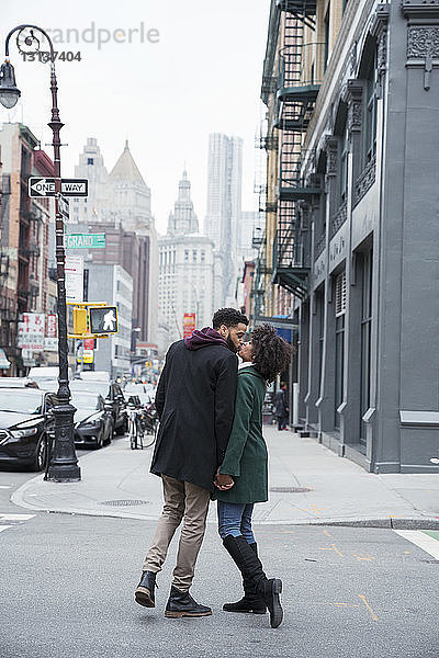 Geschäftspaar in voller Länge küsst sich stehend auf der Straße in der Stadt