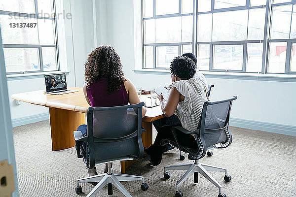 Geschäftsleute Videokonferenzen über Laptop-Computer mit einer Geschäftsfrau  während sie im Sitzungssaal sitzen