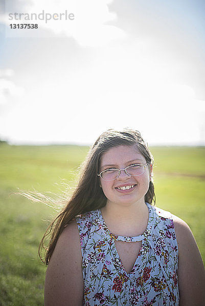 Porträt eines übergewichtigen Teenagers  der im Sommer auf dem Feld gegen den Himmel lächelt