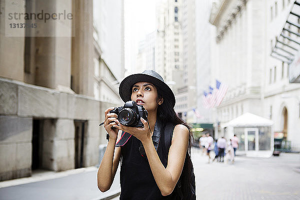 Frau mit Kamera auf Stadtstraße stehend