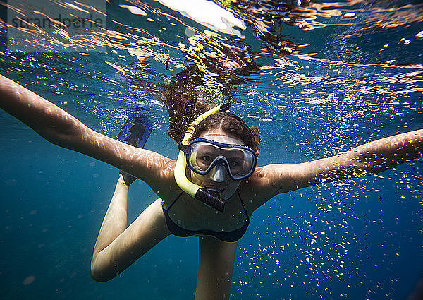 Porträt einer jungen Frau mit Schutzbrille beim Schnorcheln unter Wasser