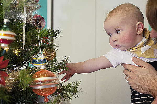 Süßes Baby mit Vater in der Nähe des Weihnachtsbaums zu Hause