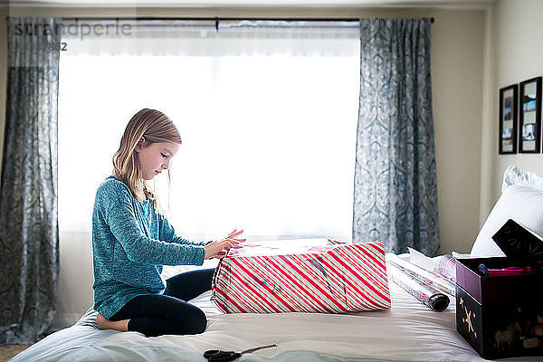 Seitenansicht eines Geschenkkartons für Mädchen  die auf dem Bett knien