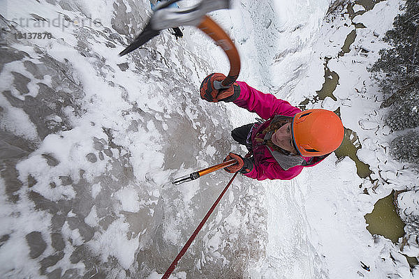 Hochwinkelaufnahme einer Wanderin beim Eisklettern