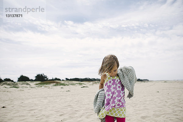 Mädchen steht auf Sand am Strand gegen den Himmel