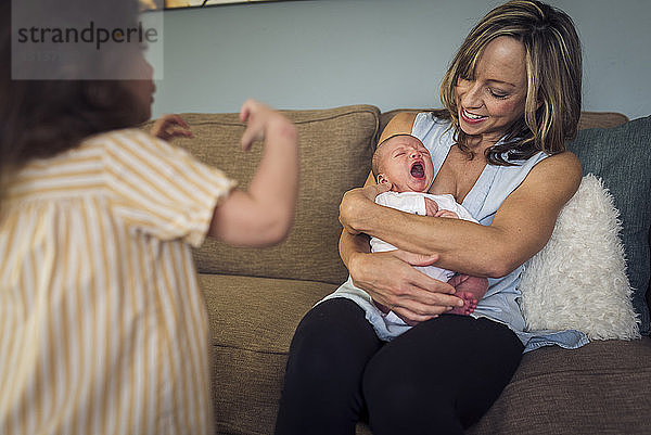 Mädchen steht bei der Mutter und sieht weinenden Sohn an