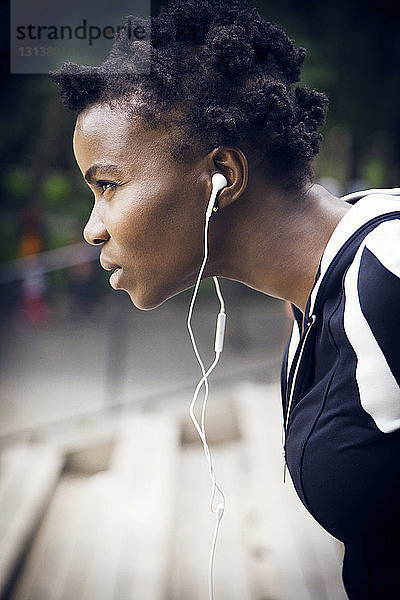 Entschlossener Sportler  der während des Trainings im Park über Kopfhörer Musik hört