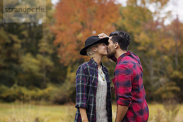Zärtlicher Mann küsst Frau im Herbst auf dem Feld