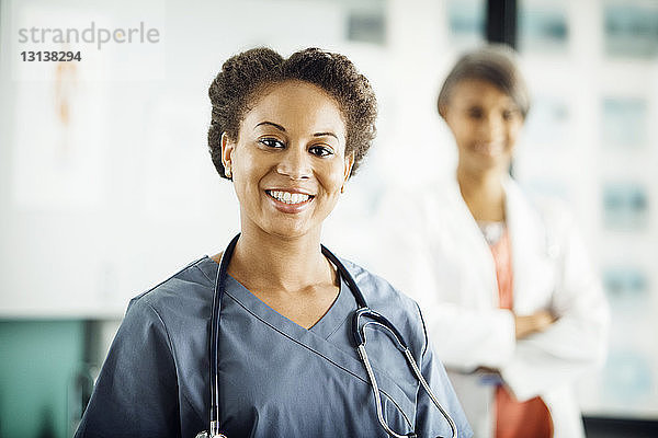 Porträt einer glücklichen Ärztin mit im Hintergrund stehender Kollegin