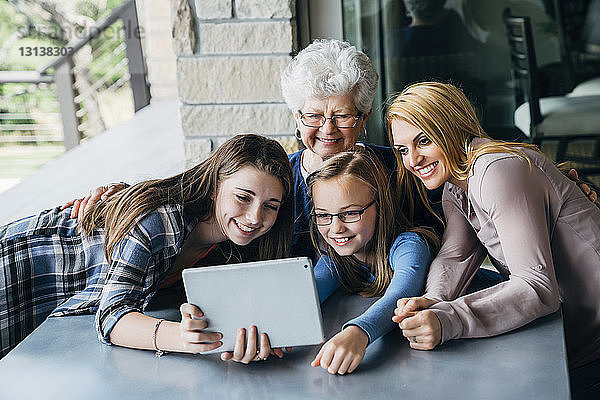 Schwestern beim Selbstausbau mit Mutter und Großmutter durch Tablet-Computer auf der Veranda