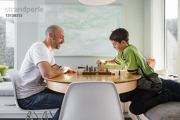 Seitenansicht von Vater und Sohn beim Schachspiel zu Hause