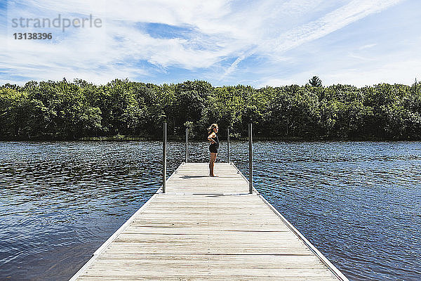 Seitenansicht eines Mädchens  das auf einem Steg über dem See gegen den Himmel steht