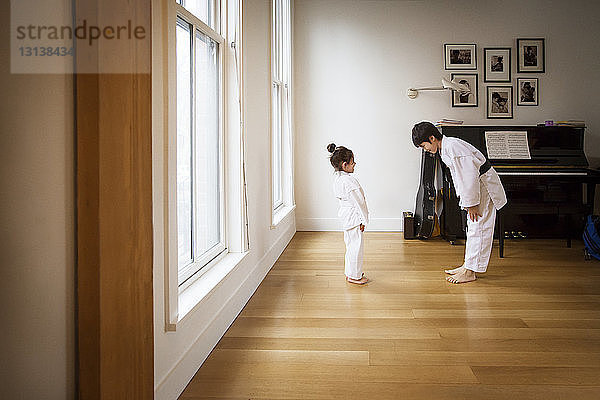 Geschwister üben Karate in hell erleuchtetem Haus