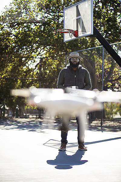 Mann fliegt Drohne auf Basketballplatz