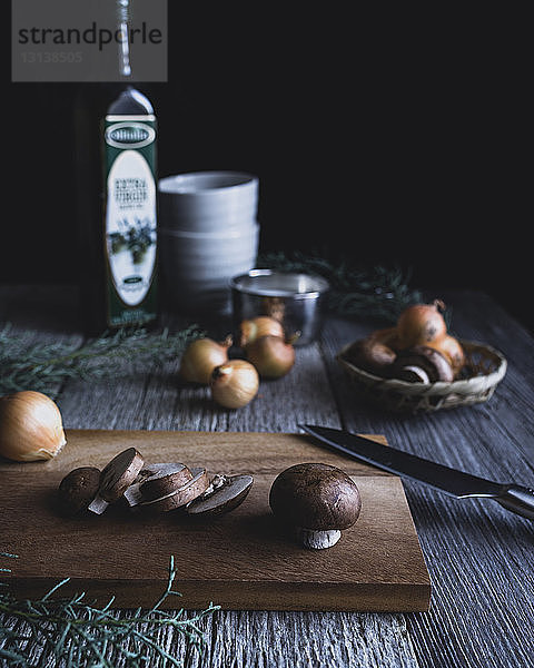 Champignons mit Zwiebel und Messer auf Schneidebrett